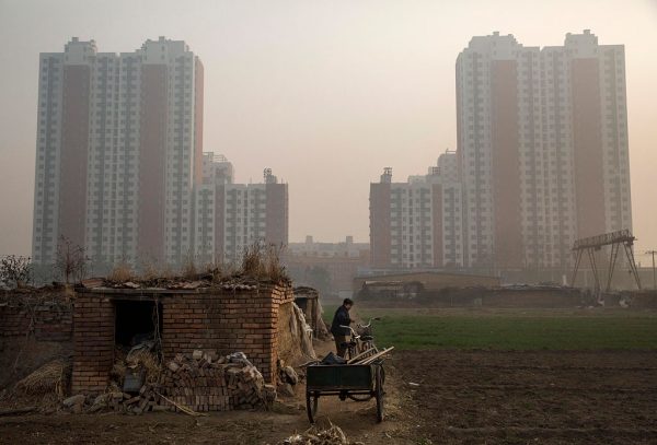 China Collects $44 Billion to Save Real Estate Developers, 500,000 Presale House Buyers Stop Mortgage Payments 8 An elderly Chinese farmer stands outside her home on farmland backdropped by a new housing development in Hebei on Nov. 21, 2014. (Kevin Frayer/Getty Images)