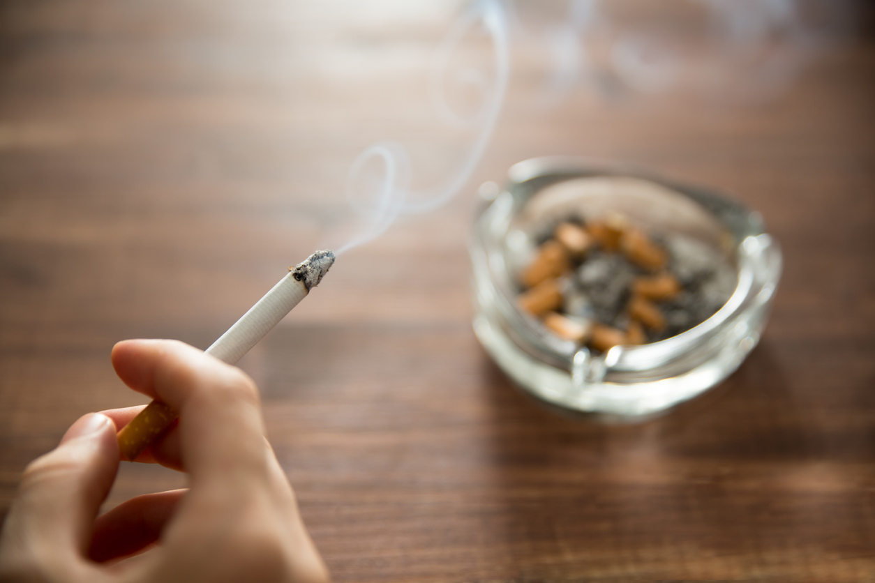 How to Dramatically Cut Your Risk of Liver Cancer 3 Woman holding burning cigarette in hand with ashtray.